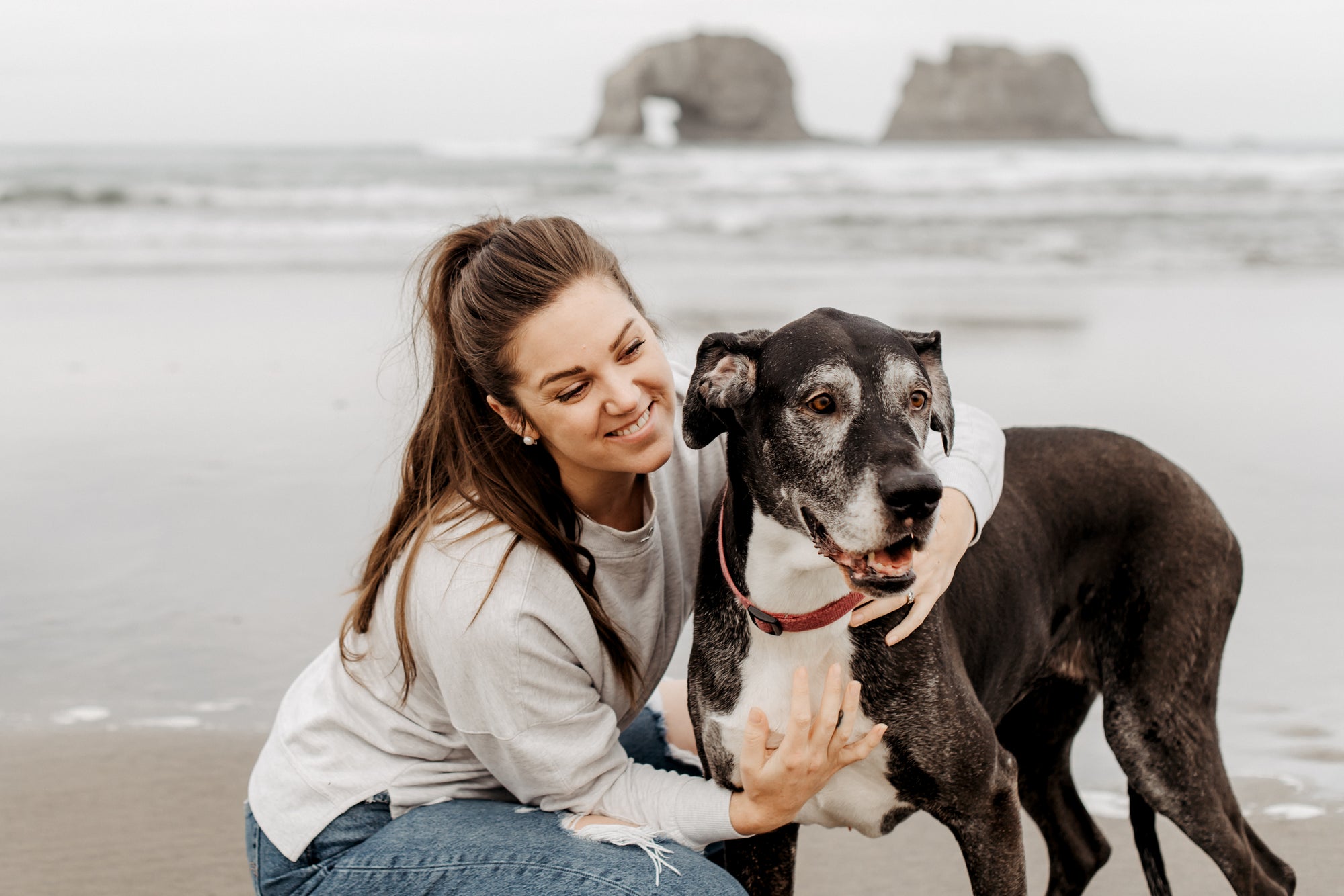 Woman and dog on a beach with a rock formation in the background